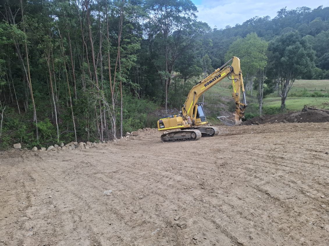 Komatsu PC200 excavator cutting a level building pad out of a timbered hillside in the Northern Rivers NSW